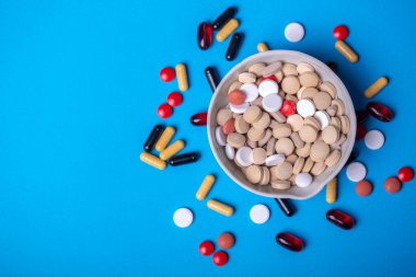 Bir kase çok renkli hapla ve farklı renk ve şekillerde diğer hapların yanında...