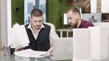 Yeni bir inşaat projesinde çalışan yakışıklı sakallı mimarlar.