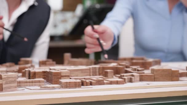 Close up of architects holding over miniature town — Stock Video