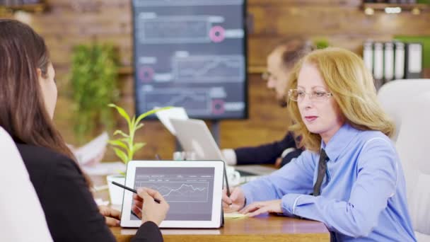 Vrouwelijke collega 's analyseren grafieken op tablet in de vergaderzaal — Stockvideo