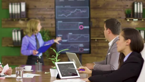 Business woman in a finance meeting pointing at graphs on tv screen — Stock Video