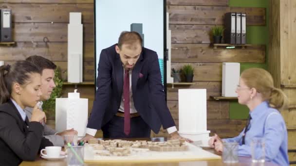 Архитектор в деловом костюме наклоняется к столу — стоковое видео