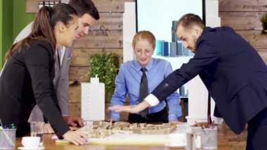 Takım elbiseli bir işadamı konferans odasında mimarlardan oluşan bir ekiple konuşuyor.