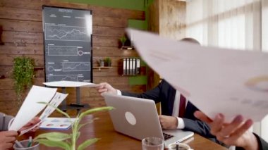 Takım elbiseli bir işadamı meslektaşına finans tabloları veriyor.