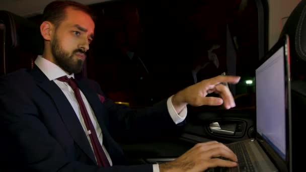 Επιχειρηματίας με κοστούμι που εργάζεται μέχρι αργά στο laptop του στο πίσω κάθισμα του αυτοκινήτου του — Αρχείο Βίντεο