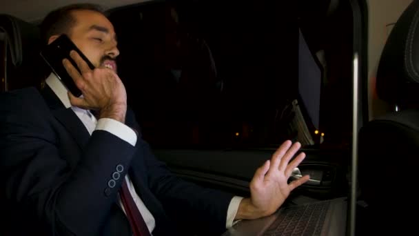 Boze zakenman schreeuwt tijdens telefoongesprek op de achterbank van zijn limousine — Stockvideo
