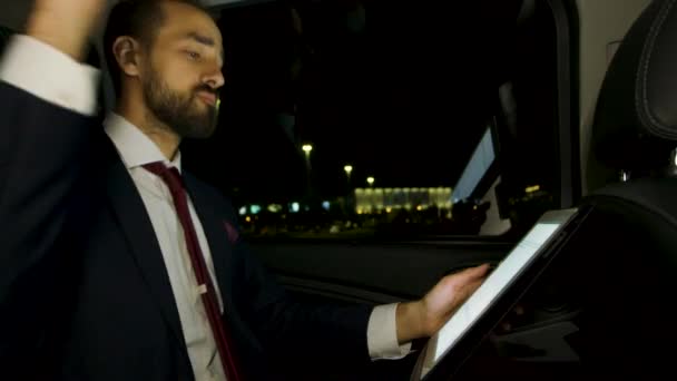 Nadšený obchodník v obleku dacing na zadním sedadle své limuzíny — Stock video