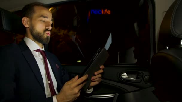 Бизнесмен во время делового видеозвонка на заднем сиденье своей роскошной машины — стоковое видео