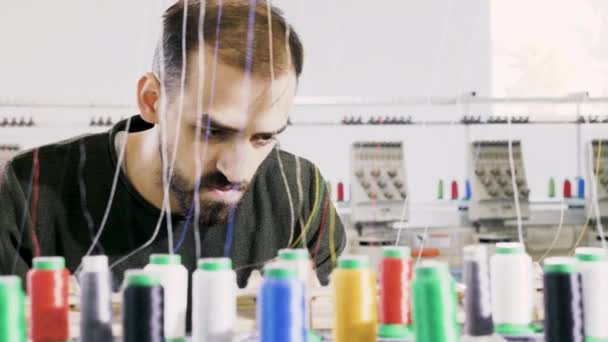 Muž v továrně na tkaniny kontroluje stroje na šití bavlny — Stock video
