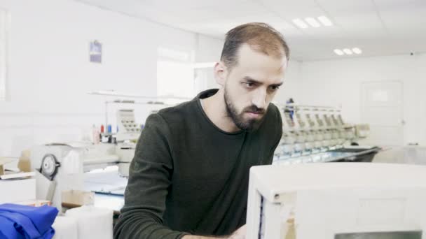 Uomo che lavora su computer di macchina per cucire — Video Stock