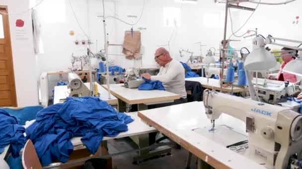 Retrato de un hombre en una máquina de coser en una fábrica de costura — Vídeo de stock