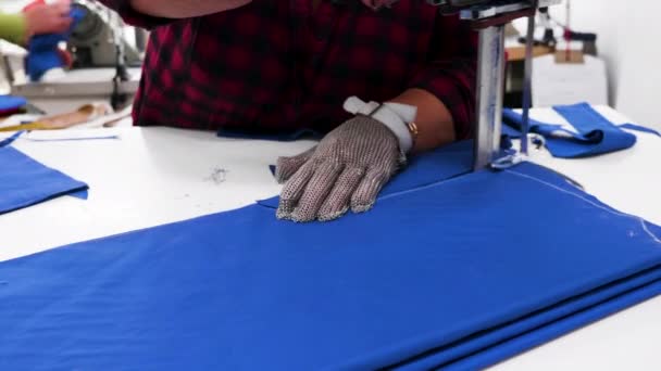 Работница с электрическим ножом, разрезающая ткань на текстильной фабрике — стоковое видео