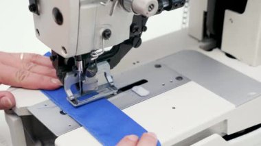 Düğmelere delik açmak için temizleme makinesi kullanan kadın işçi