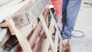 Tahta paletleri kesmek için elektrikli testere kullanan adam.