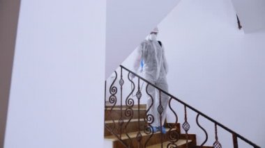 Tehlikeli madde giysisi giymiş ön hat çalışanı dezenfekte ediyor.