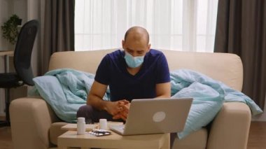 Doktoruyla görüntülü görüşmede maske takan bir adam.