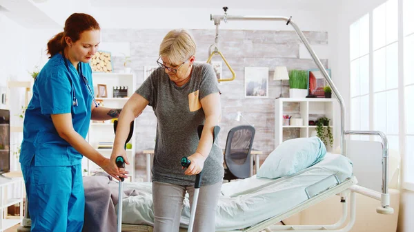 Enfermera en casa de retiro ayudando a una anciana a recuperar su fuerza muscular —  Fotos de Stock