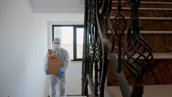 Доброволец в защитном костюме, доставляющий благотворительную еду
