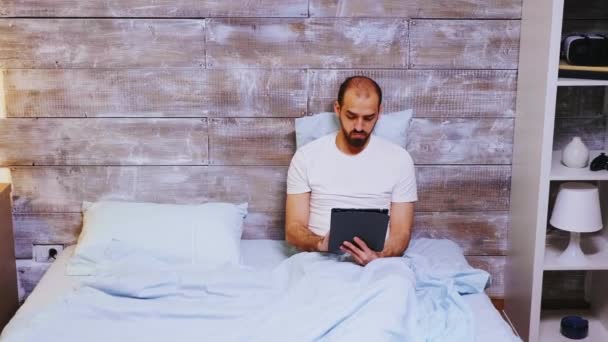 Hombre en pijama surfeando en tableta — Vídeos de Stock