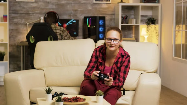 Жінка сидить на дивані у вітальні грає у відеоігри — стокове фото
