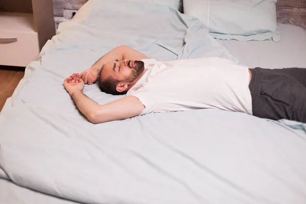 Hombre cansado acostado en una cama cómoda — Foto de Stock