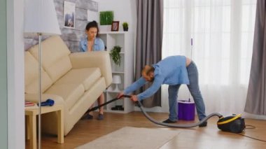 Elektrik süpürgesi kullanan adam.