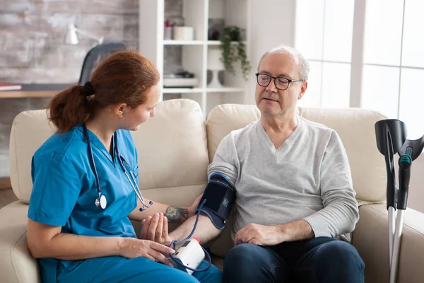 Un bărbat în vârstă care alăptează acasă cu dispozitiv digital de tensiune arterială — Fotografie, imagine de stoc