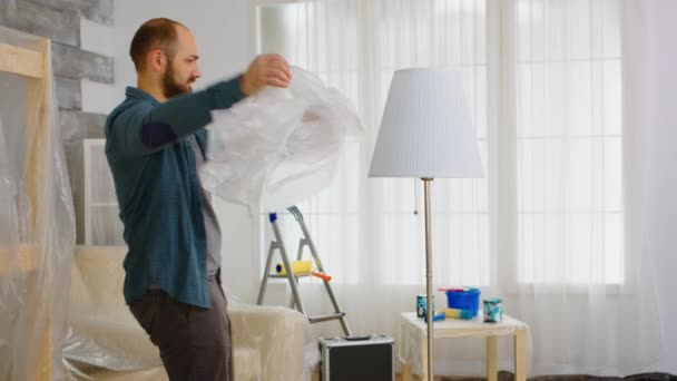 Mann wickelt Lampe mit Plastik ein — Stockvideo