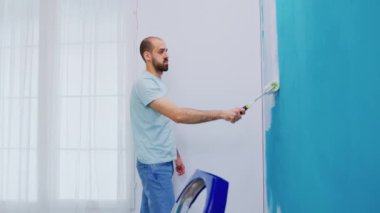 Duvara beyaz boya sürüyorum.