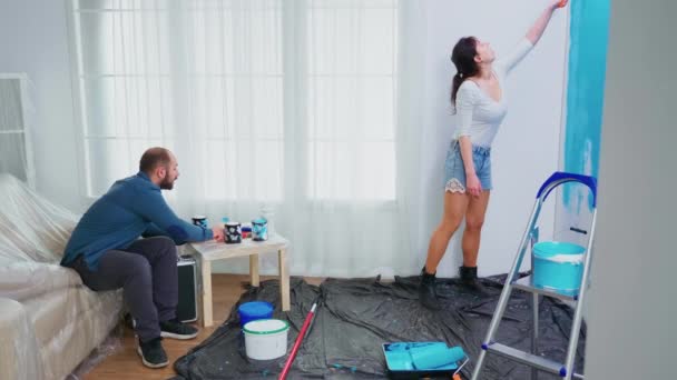 Vrouw schilderij muur met roller borstel — Stockvideo