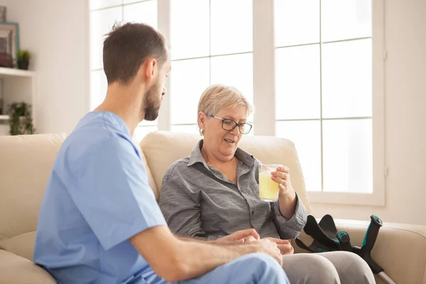 Männlicher Arzt hilft Seniorin bei der Einnahme ihrer Medizin — Stockfoto