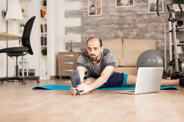 Homme faisant jambes étirant sur tapis de yoga — Photo