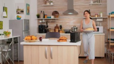 Pijamalı ev hanımı kahvaltı hazırlıyor.