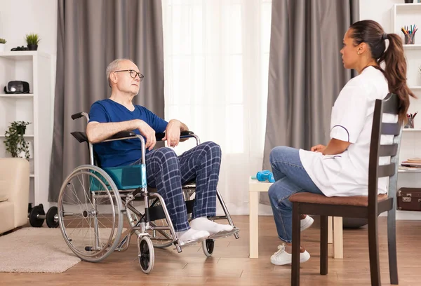 Persona sulla sedia a rotelle che parla con l'infermiera — Foto Stock