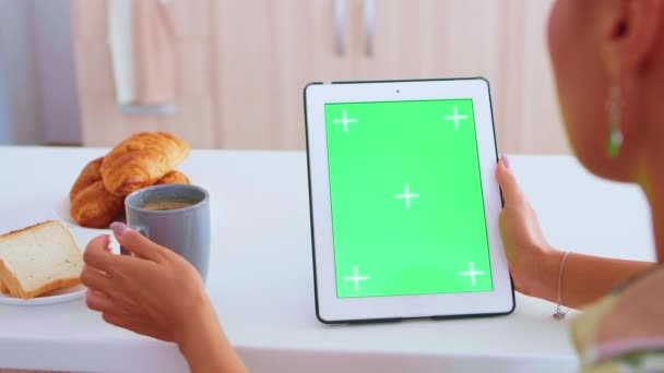 Sentado à mesa olhando para tablet computador com tela verde — Vídeo de Stock