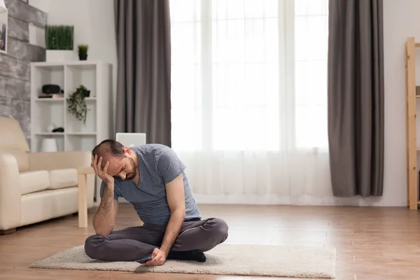 Поганий чоловік сидить на килимі у вітальні — стокове фото