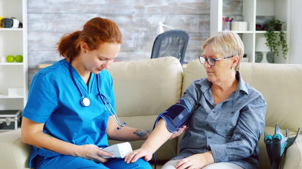 Medico femminile che prende la pressione sanguigna della donna anziana — Foto Stock