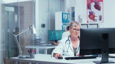 Bilgisayar üzerinde çalışan deneyimli kıdemli kadın doktor.