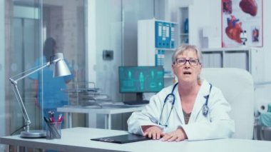 Otantik deneyimli yaşlı kadın doktor kameraya konuşuyor.