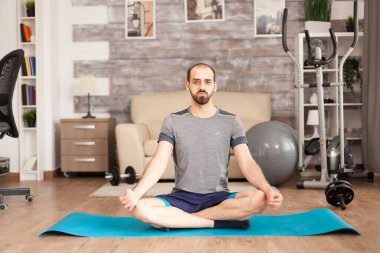 Lotus yogası yaparken spor kıyafeti giyen bir adam.