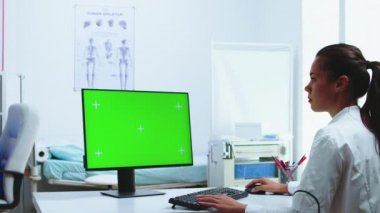 Yeşil ekranlı bilgisayar kullanan bir doktor