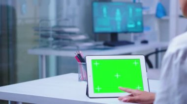Tıp doktoru beyaz önlük giyiyor, tablet bilgisayar kullanıyor.