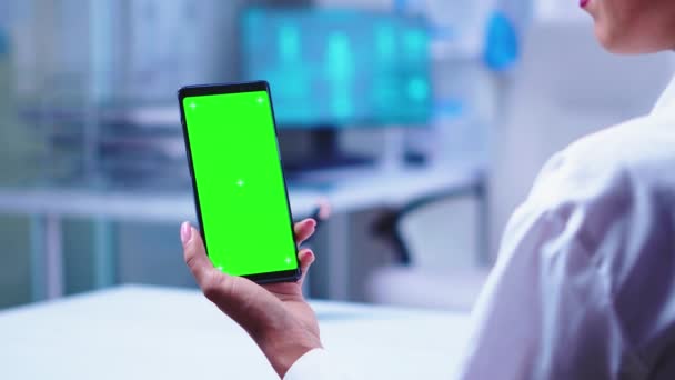 Медик в больничном кабинете держит телефон с зеленым экраном — стоковое видео