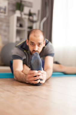 Spor kıyafetli bir adam bacaklarını açıyor.