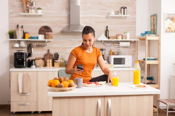 Nachrichten am Telefon in der Küche lesen — Stockfoto