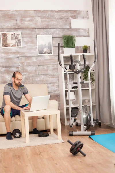 Mann in Sportkleidung sucht auf Laptop nach Körperübungen — Stockfoto