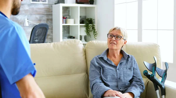 Старша стара жінка сидить на дивані в будинку престарілих розмовляє з лікарем — стокове фото