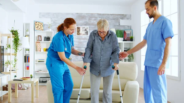 Старшая женщина с костылями получает помощь для медсестры — стоковое фото