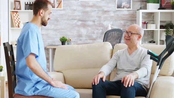 Пенсіонер у будинку престарілих розмовляє з медсестрою чоловічої статі — стокове фото
