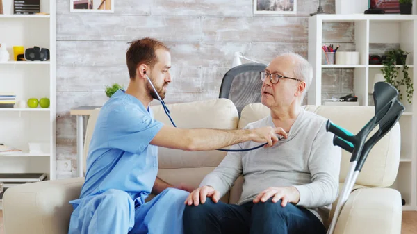Inyección reveladora de un joven enfermero escuchando el latido del corazón de un anciano jubilado —  Fotos de Stock